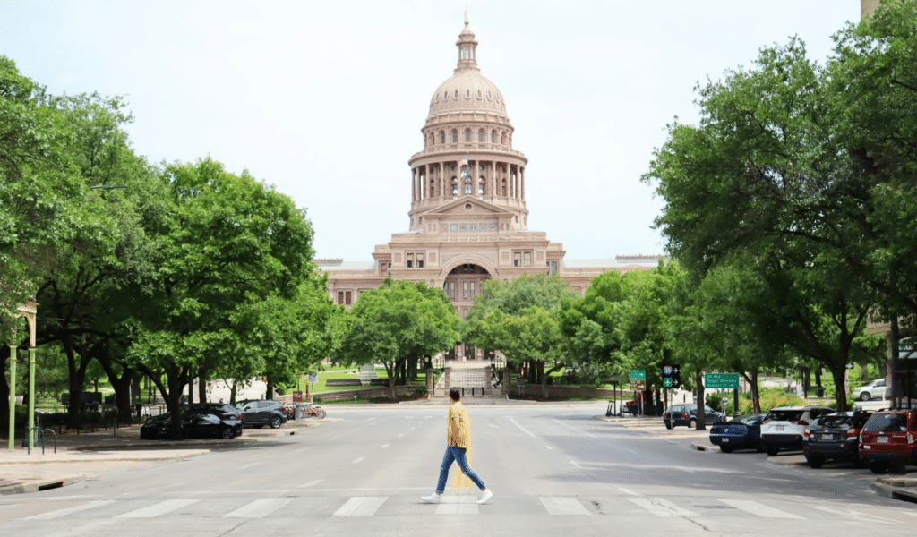 The Texas State Capitol in Austin with a person walking in front of it